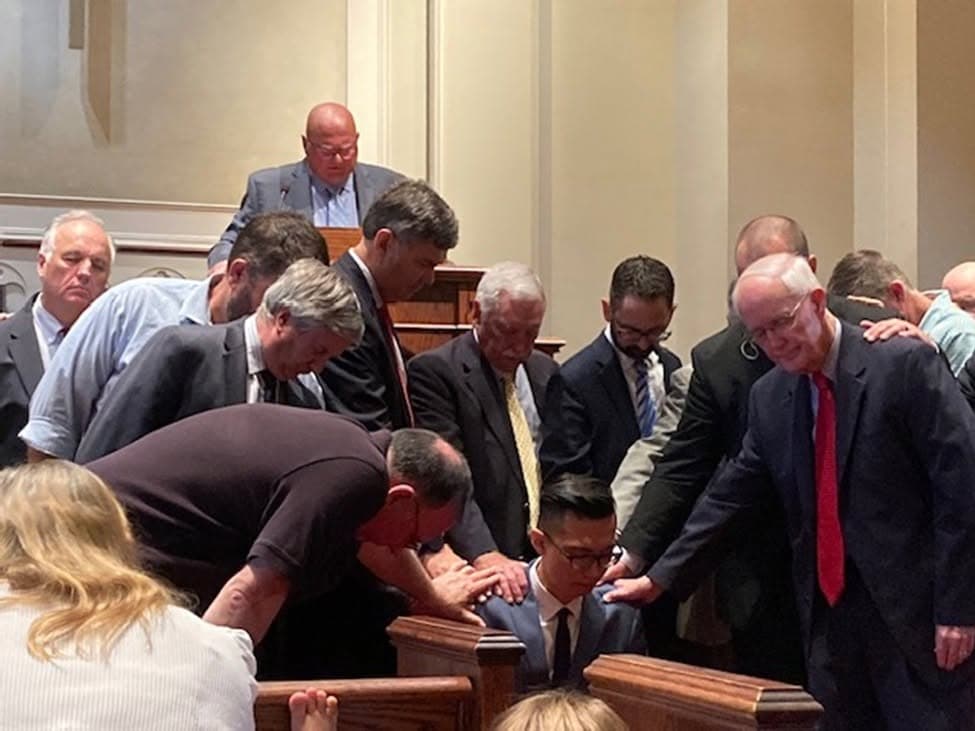 Church leaders laying hands on Jae in prayer at his ordination